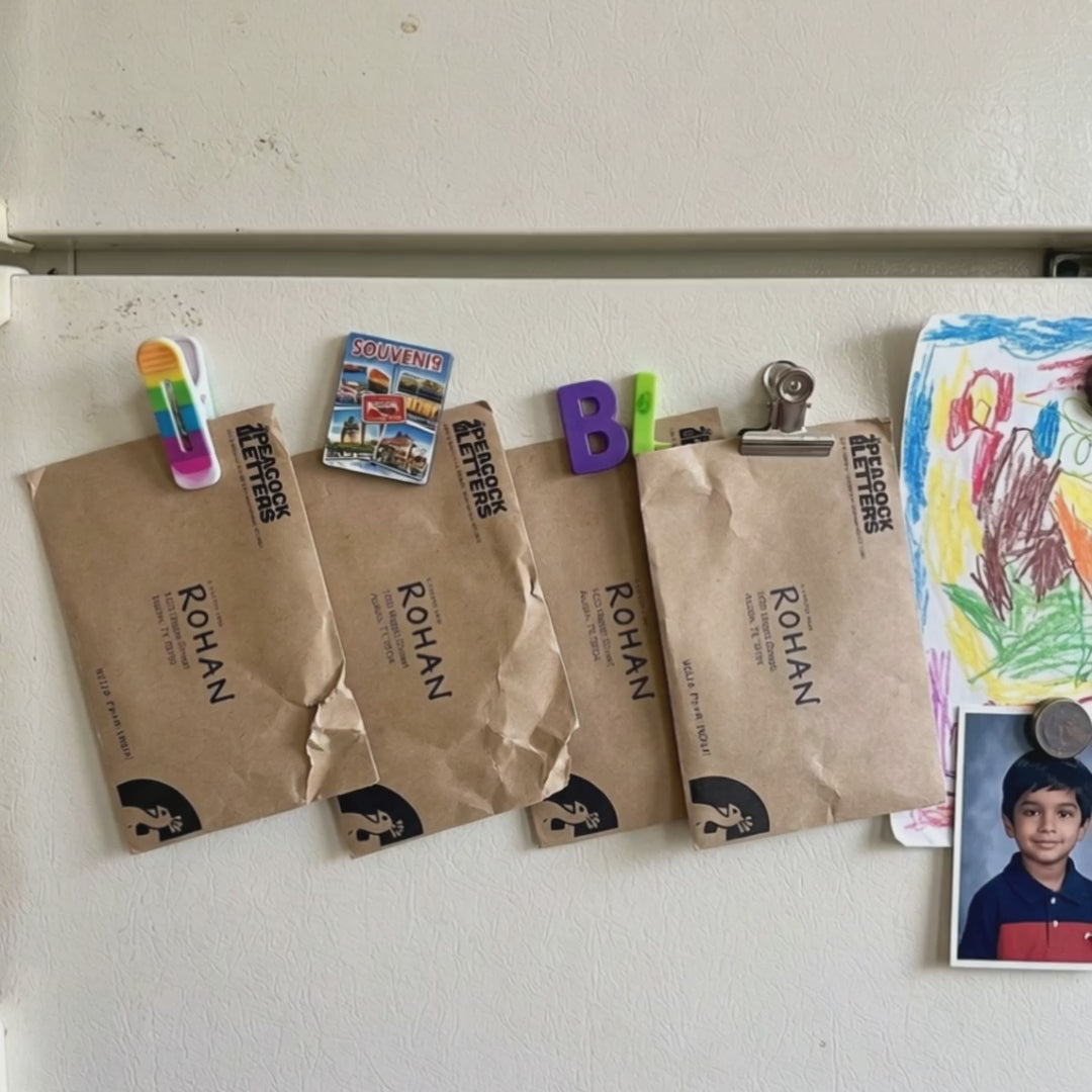 Child clipping Peacock Letters envelopes addressed to them onto the fridge